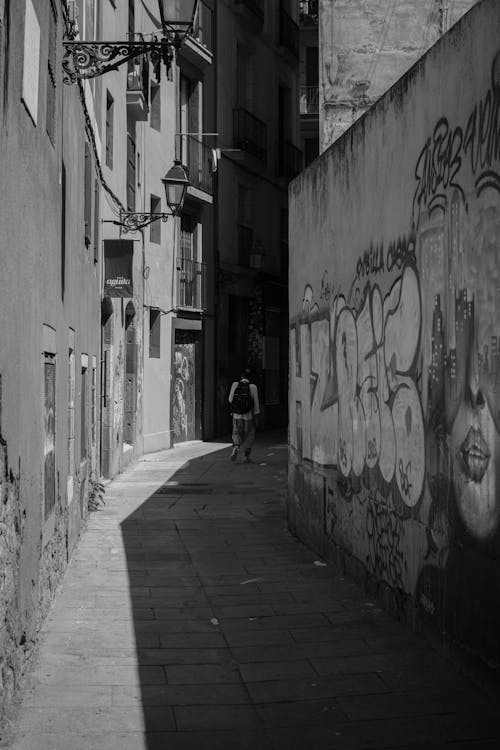 Man Walking in Narrow Alley in Town in Black and White