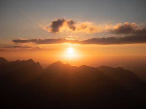 Captivating sunrise over Glarus mountains with dramatic clouds and silhouette.