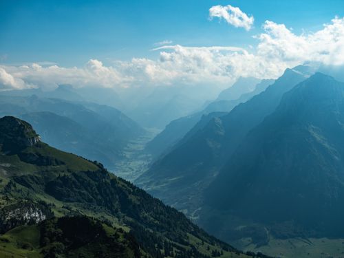 Free Stunning mountain valley with green peaks under a blue sky with clouds, perfect for nature enthusiasts. Stock Photo