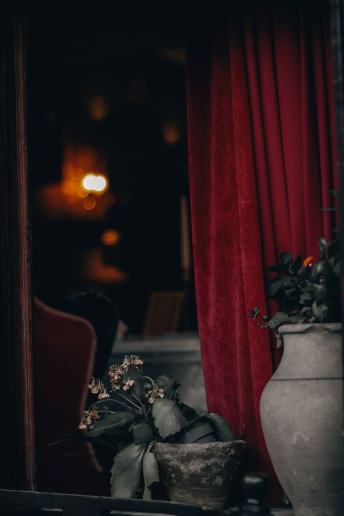 Free A dimly lit interior with red curtains and stone vases, creating a cozy, atmospheric setting. Stock Photo