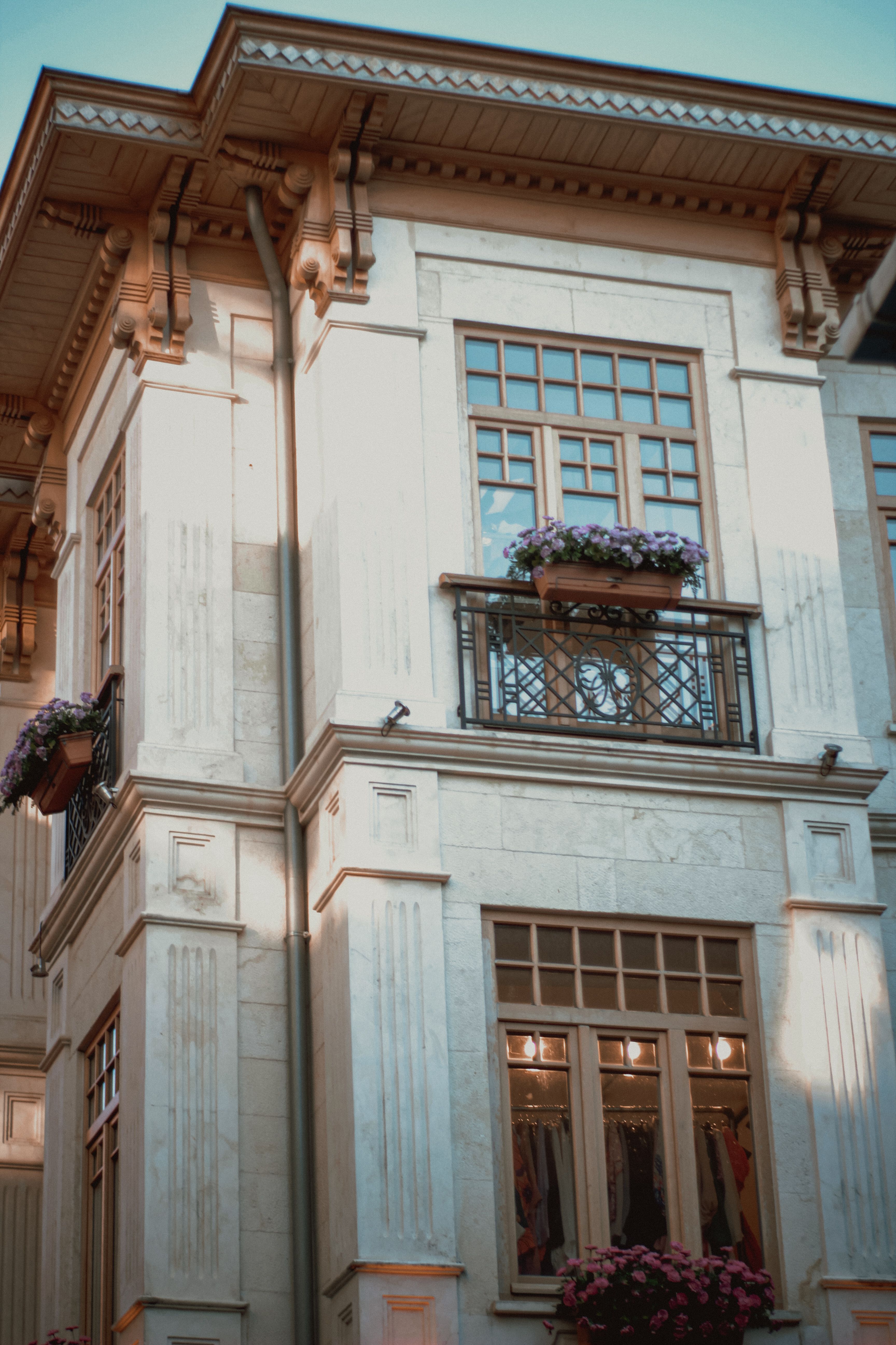 Detailed facade of a historic house with balconies adorned with flowers, captured in soft lighting.