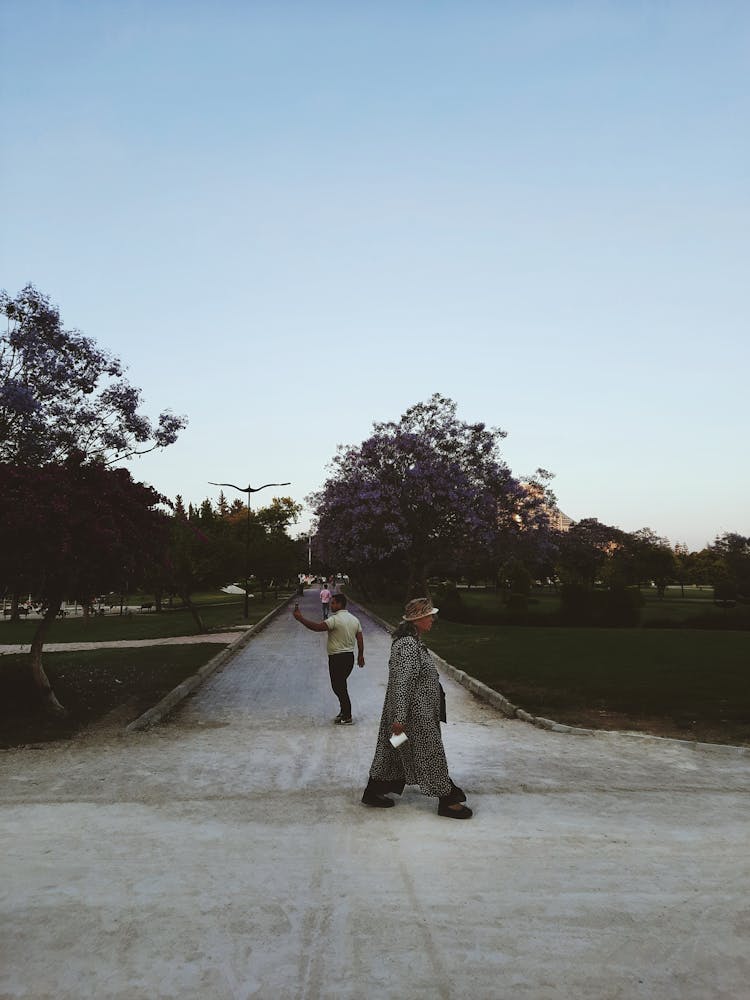 People Walking On A Concrete Pathway At A Park