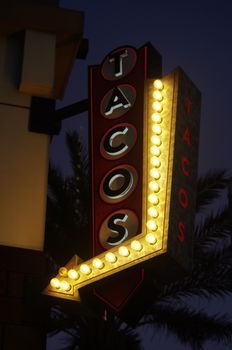Neon taco sign glowing brightly at night in Los Angeles, depicting nightlife and urban vibes.