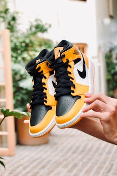 Vibrant yellow and black Air Jordan sneakers held outside, showcasing style and athleticism.