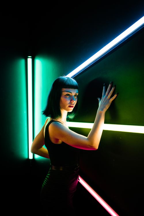 Free Portrait of a woman in a dark room with vibrant neon lights, creating a modern and artistic vibe. Stock Photo