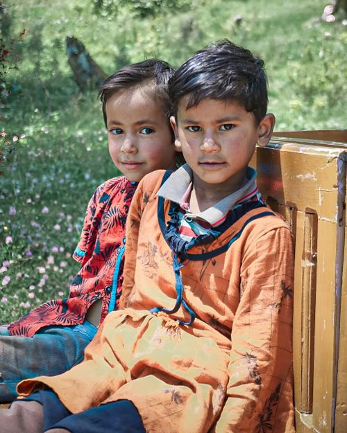 Free Two boys in colorful clothing sitting outdoors, showcasing innocence and friendship in a natural setting. Stock Photo