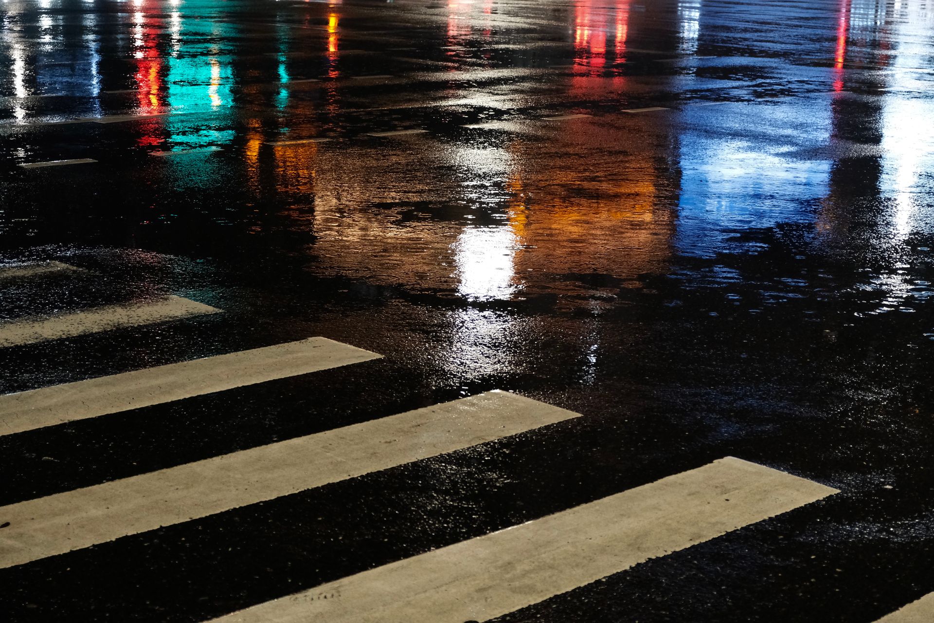 Wet asphalt of a city street at night with rain and water reflections