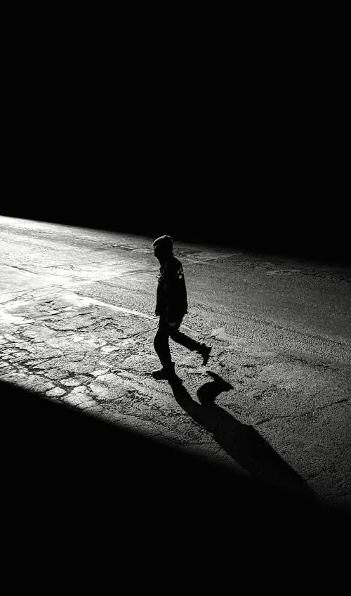 Free Silhouette of Person Walking on Asphalt Road Stock Photo