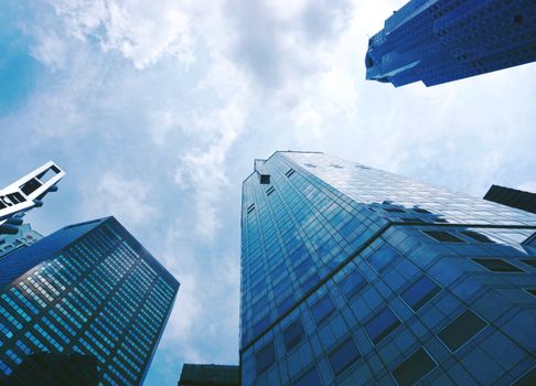 Low-angle view of towering skyscrapers with glass facades against a blue sky, reflecting modern architecture.