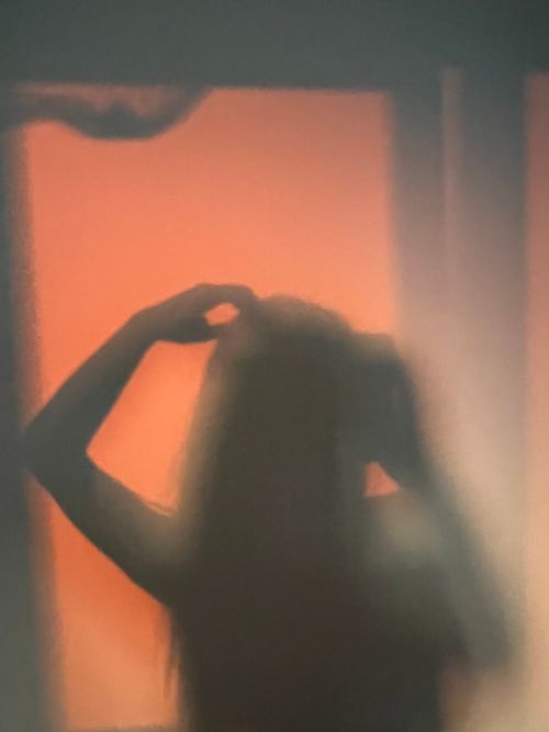 Free Artistic silhouette of a woman with hand on head, captured through sheer fabric. Stock Photo