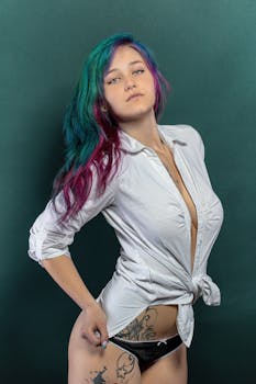 Stylish portrait of a woman with colored hair posing in a studio setting.