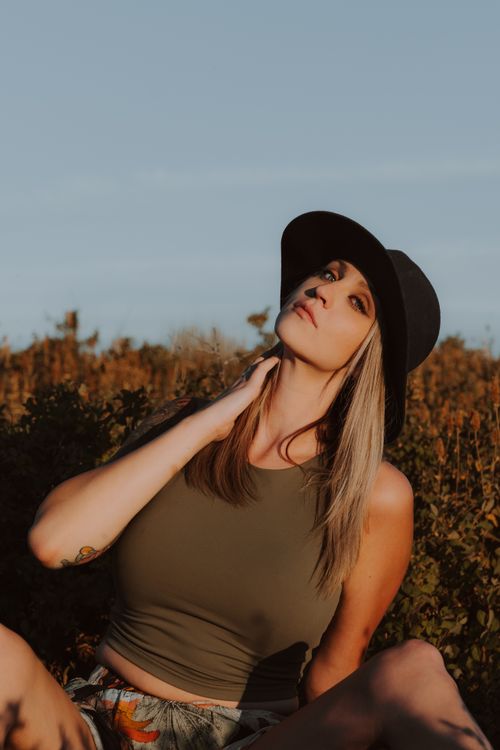 Free Stylish woman posing outdoors with a black hat under soft daylight. Stock Photo