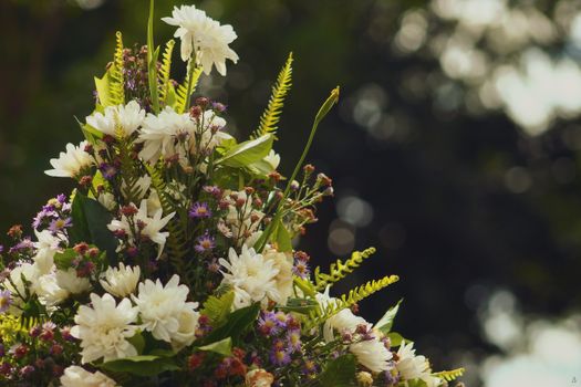Beautiful floral bouquet featuring white and purple flowers with greenery, captured in natural outdoor lighting.