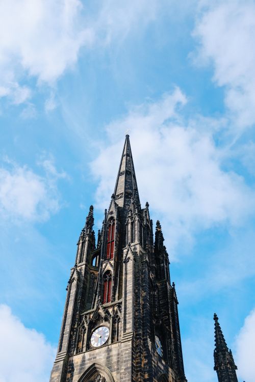 Free Stunning view of a Gothic spire with clock set against a bright blue sky in Edinburgh. Stock Photo