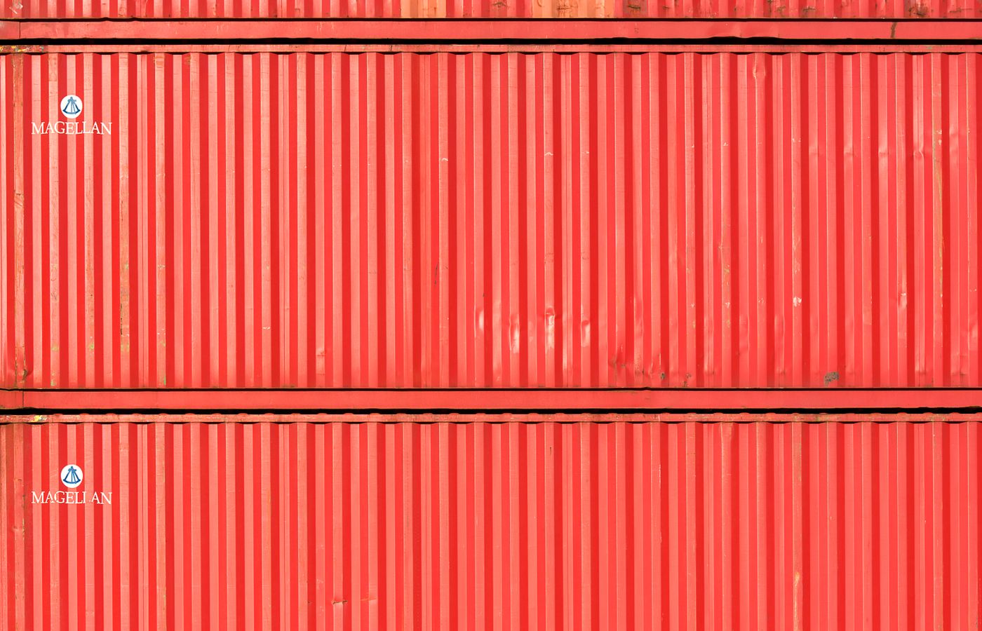 Close-up of stacked red cargo containers, providing a vibrant industrial texture.