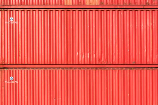 Close-up of stacked red cargo containers, providing a vibrant industrial texture.