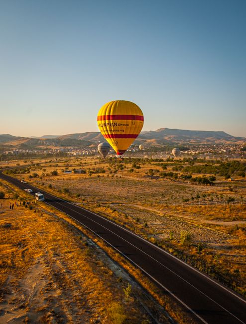 Vibrant hot air balloon soaring over Cappadocia's unique terrain during sunrise.