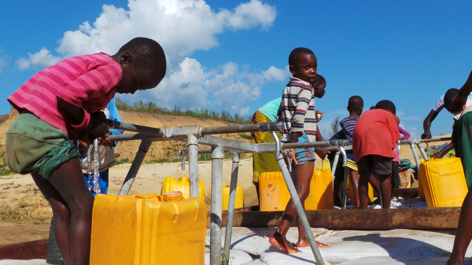 Children filling up Yellow Containers with Water