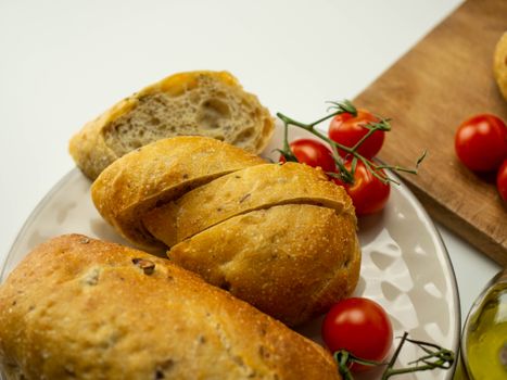 Close-up of sliced artisan ciabatta with cherry tomatoes on a rustic wooden board, perfect for culinary inspirations.