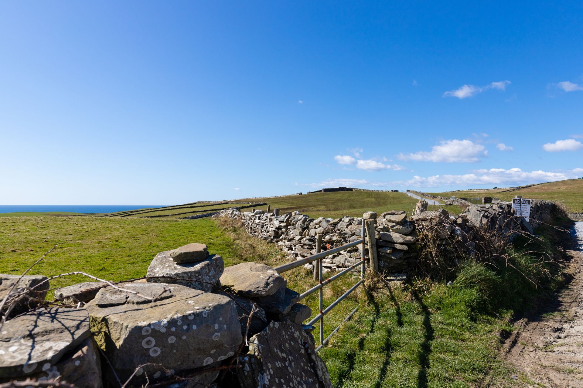 Explore the serene landscape of rural Ireland with blue skies and stone fences.