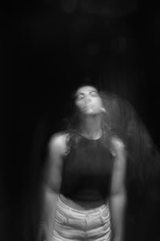 Artistic monochrome portrait of a woman with blurred motion on a black background.