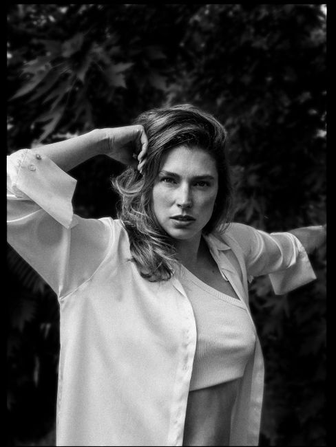 Black and white photo of a stylish woman posing outdoors with a confident expression.
