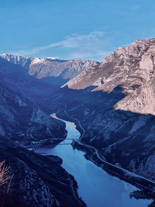 Free A breathtaking aerial shot of a river winding through rocky mountains under a blue sky. Stock Photo