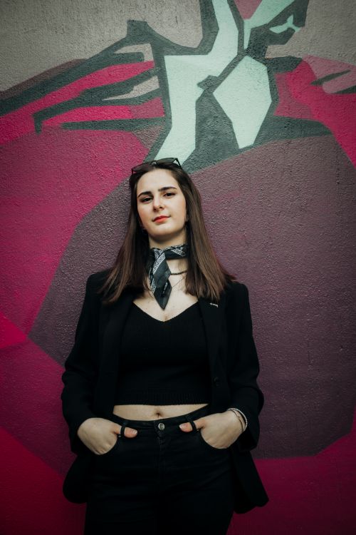 Free Chic woman in a black blazer poses confidently against a colorful graffiti wall in İzmir, Turkey. Stock Photo