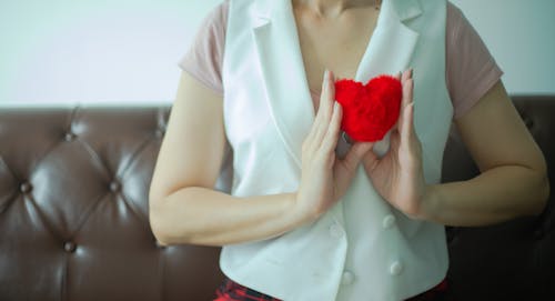 Woman in White Vest Holding a Red Heart