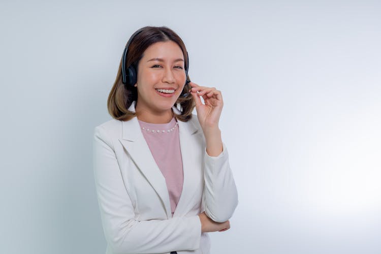 Smiling Woman In White Blazer Holding Her Headset