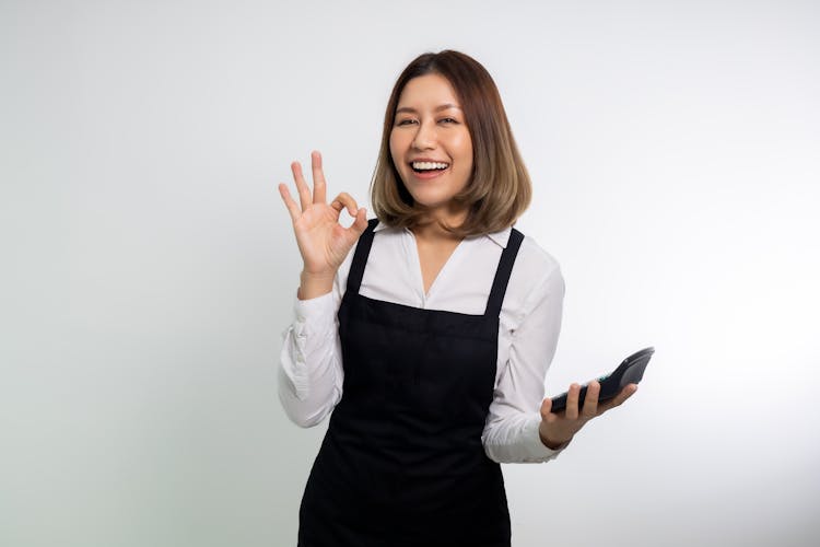 Woman In Black Apron Holding A Calculator