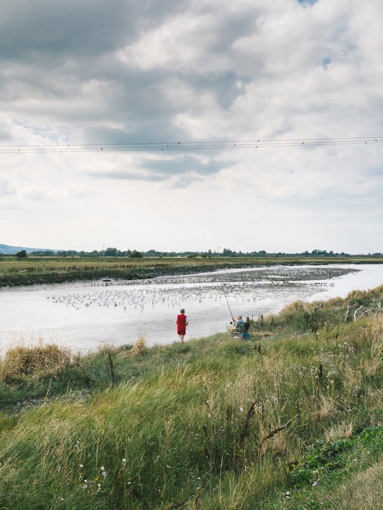 People Fishing On River Bank