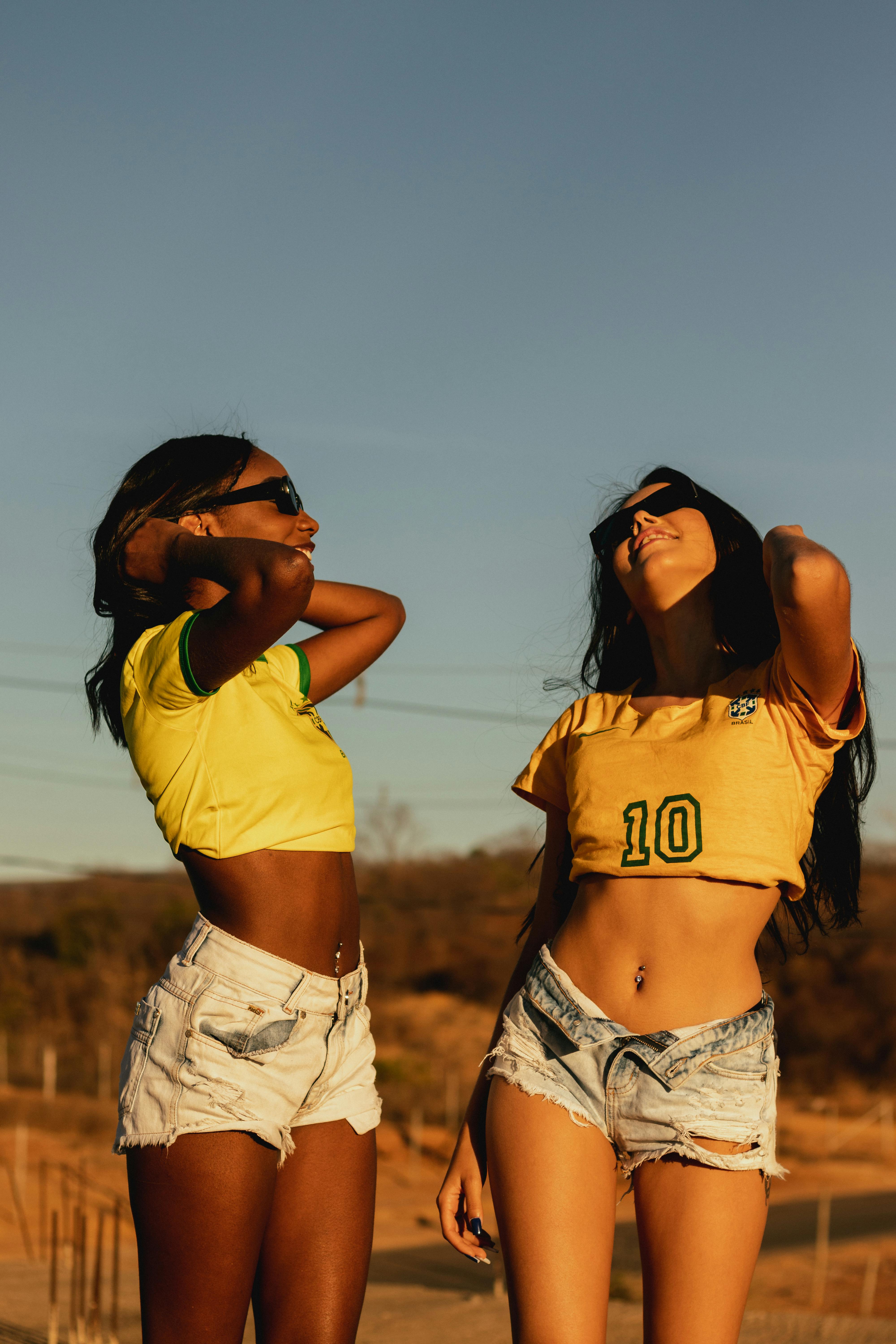 Two stylish women in shorts and sunglasses enjoy a sunny day outdoors, showcasing summer fashion.