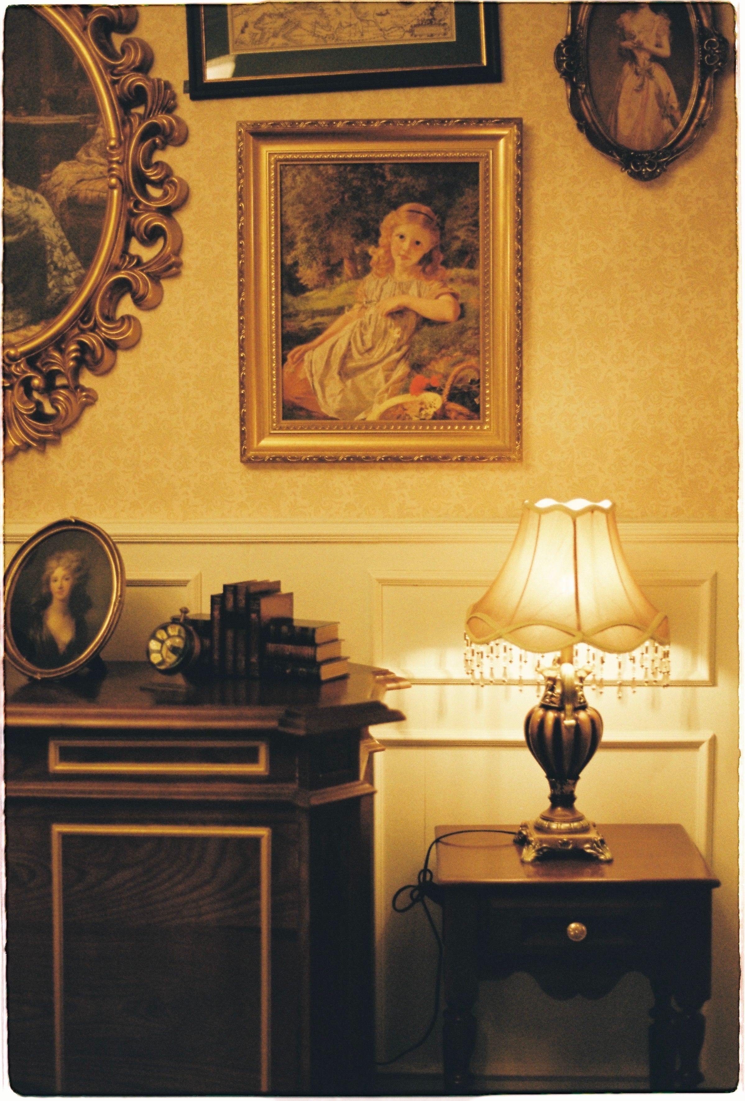 Charming vintage room with classic decor and warm lighting, featuring paintings and antique furniture.
