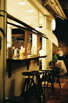 Outdoor café with wooden stools and umbrella at night, warm ambiance