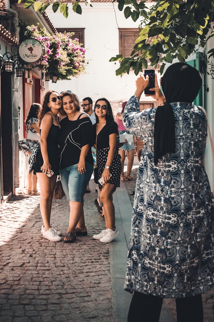 A Woman In A Hijab Taking A Picture Of A Group Of Women