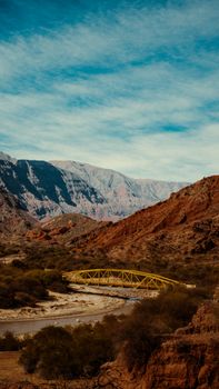 Explore the serene countryside featuring a steel bridge over a river set against majestic mountains.