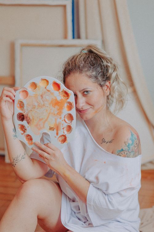 Free Portrait of a smiling woman artist with a paint palette in her art studio. Stock Photo