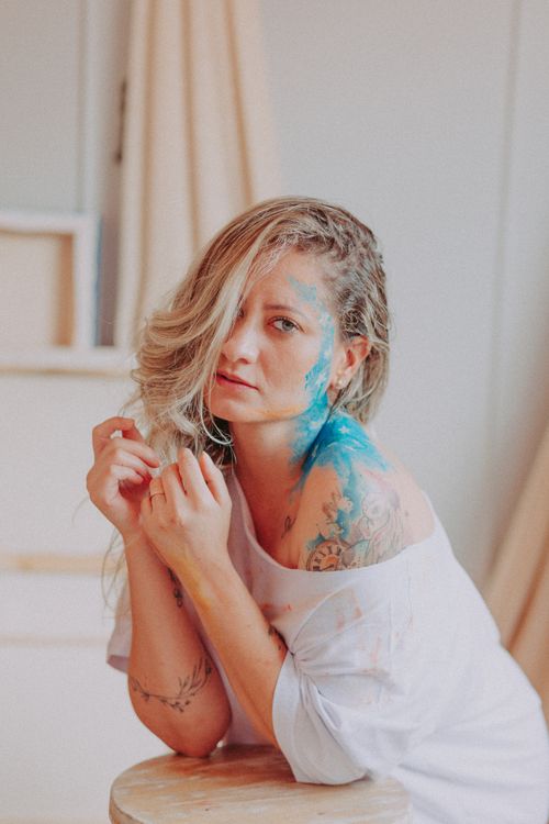 Free A thoughtful woman with body paint and tattoos posing indoors, showcasing artistic beauty. Stock Photo