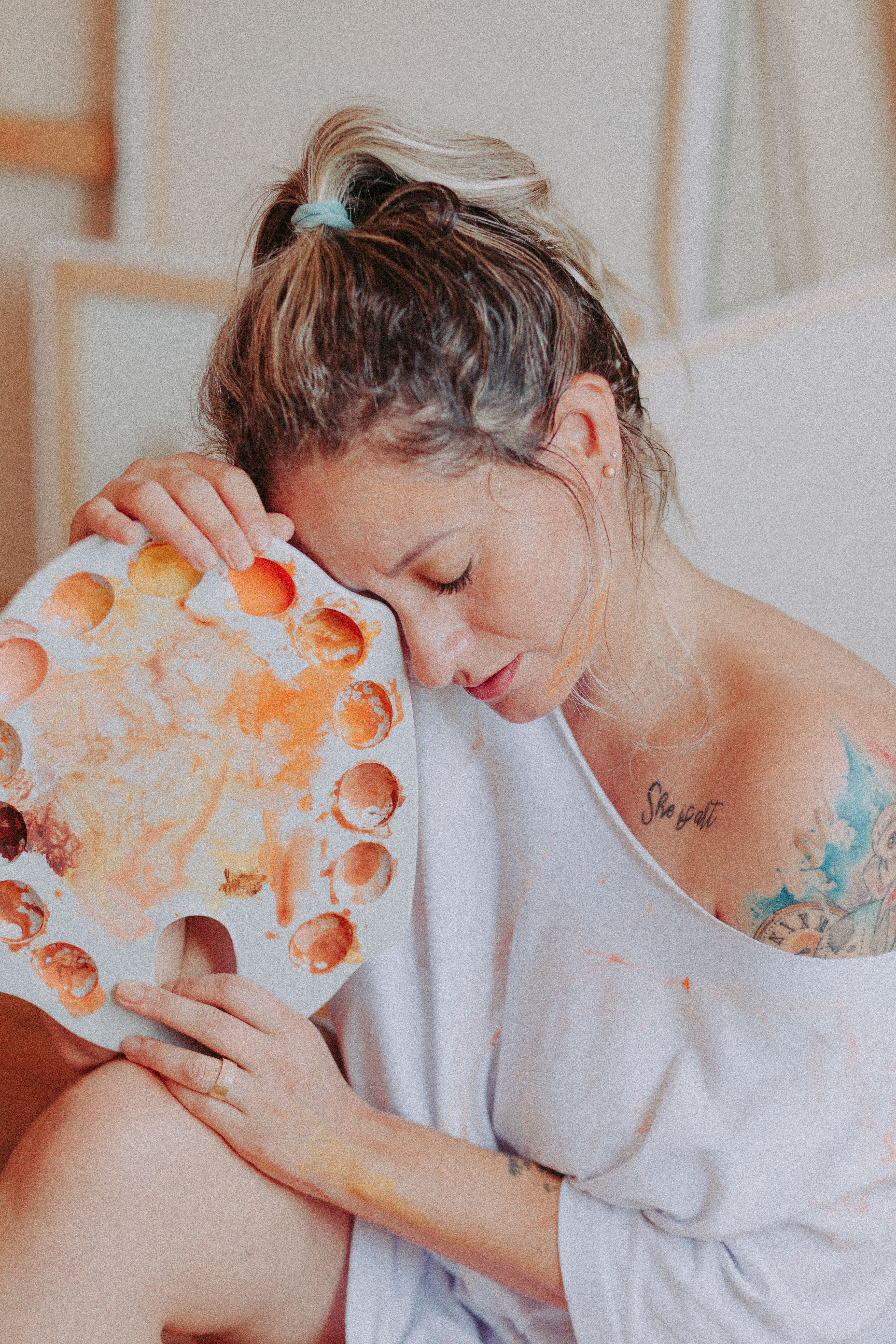 A thoughtful artistic portrait of a woman holding a paint palette, showcasing creativity and expression.