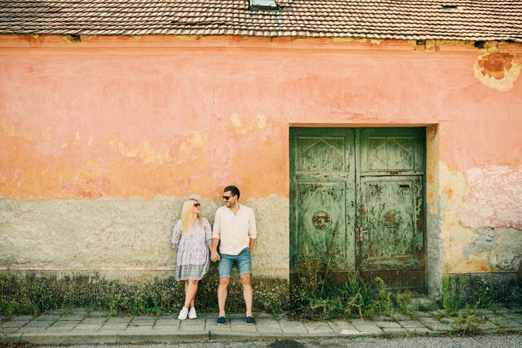 Woman And Man Holding Hands By Door Of Building