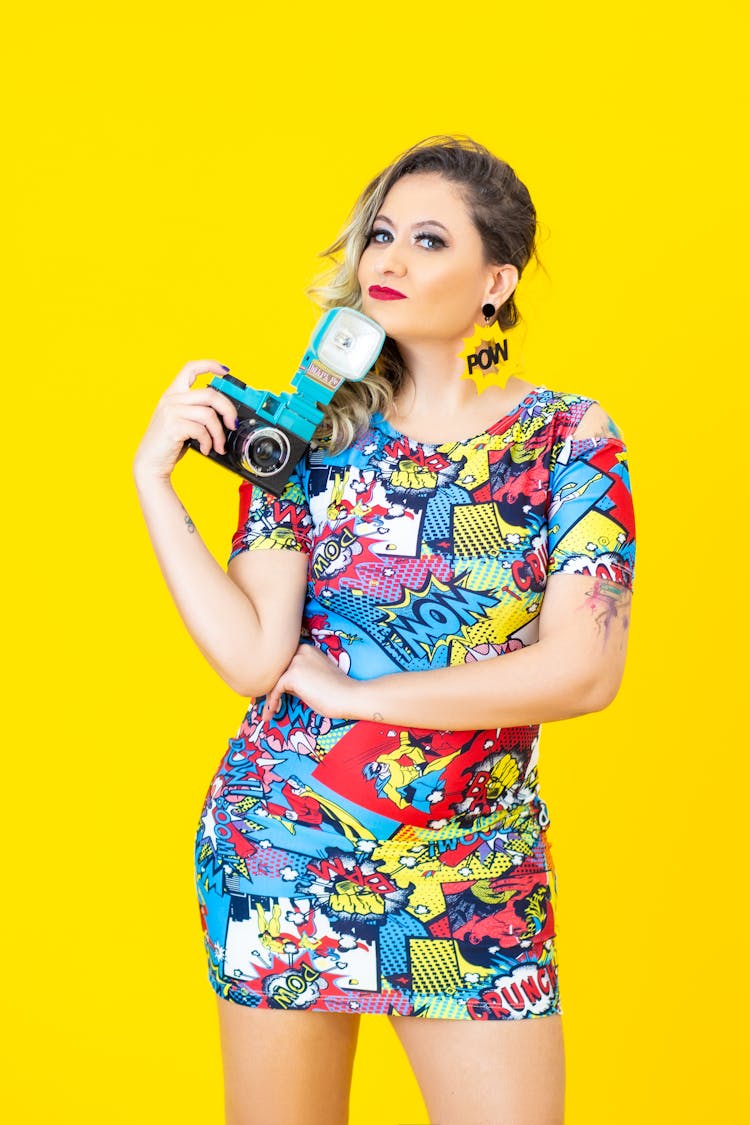 A Woman In A Comic Designed Dress Holding A Camera