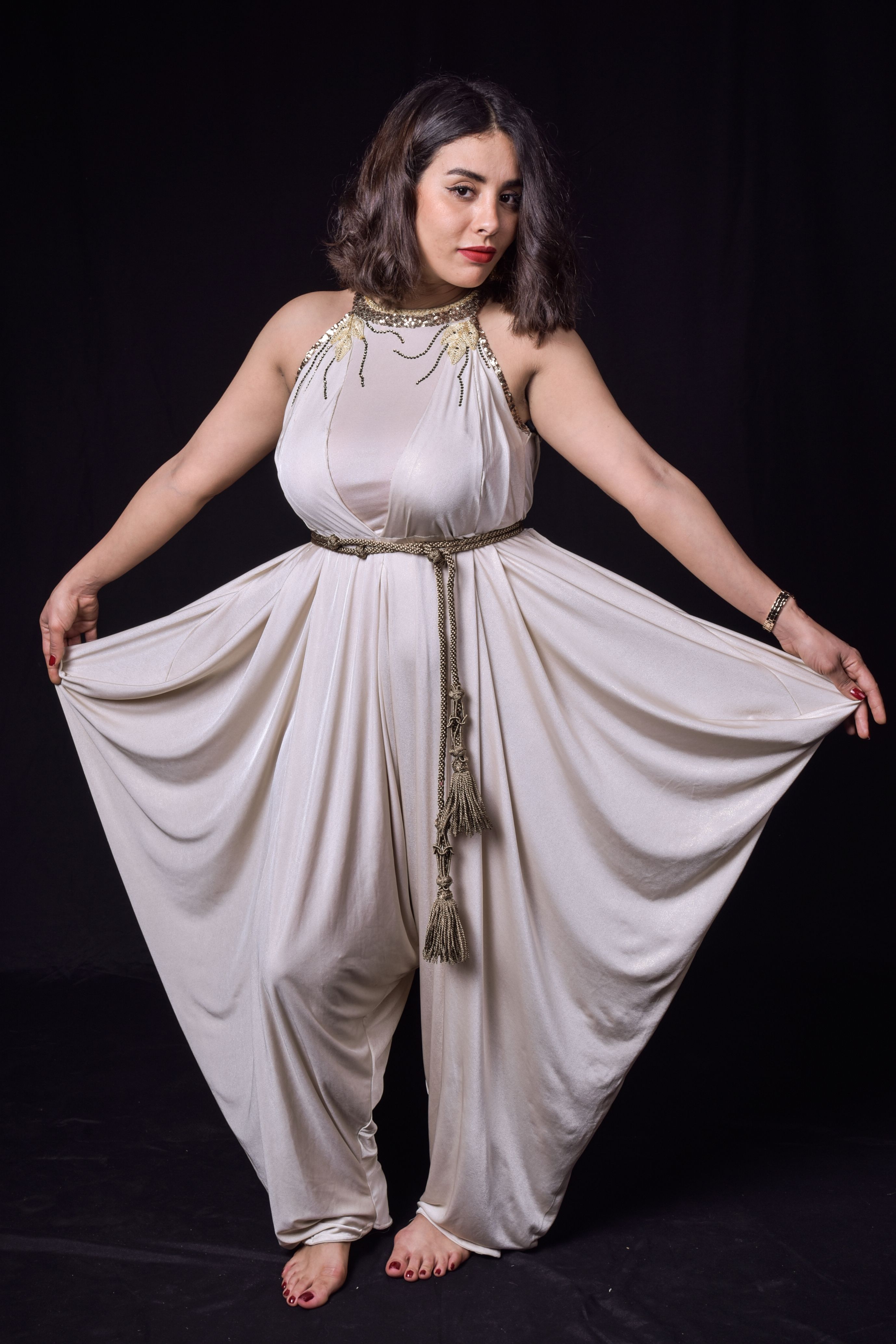 Portrait of a woman in a stunning white gown posing against a dark background.