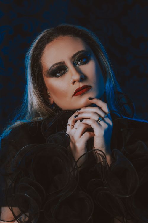 Free Striking portrait of a woman with bold eye makeup and red lips set against a dark background. Stock Photo