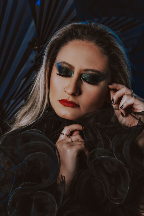 Free Close-up portrait of a woman with closed eyes showcasing dramatic eye makeup and red lips. Stock Photo