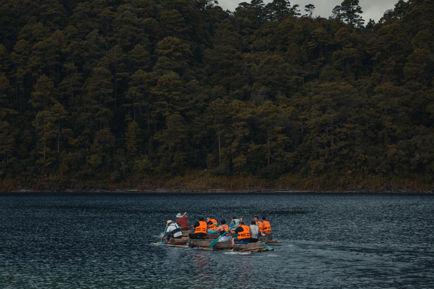 People paddling a kayak through a calm forest river