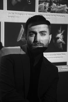 A dramatic black and white portrait with striking shadows cast across the face.