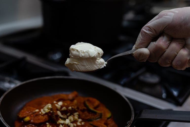 Hand In Glove Holding Cream Over Pan