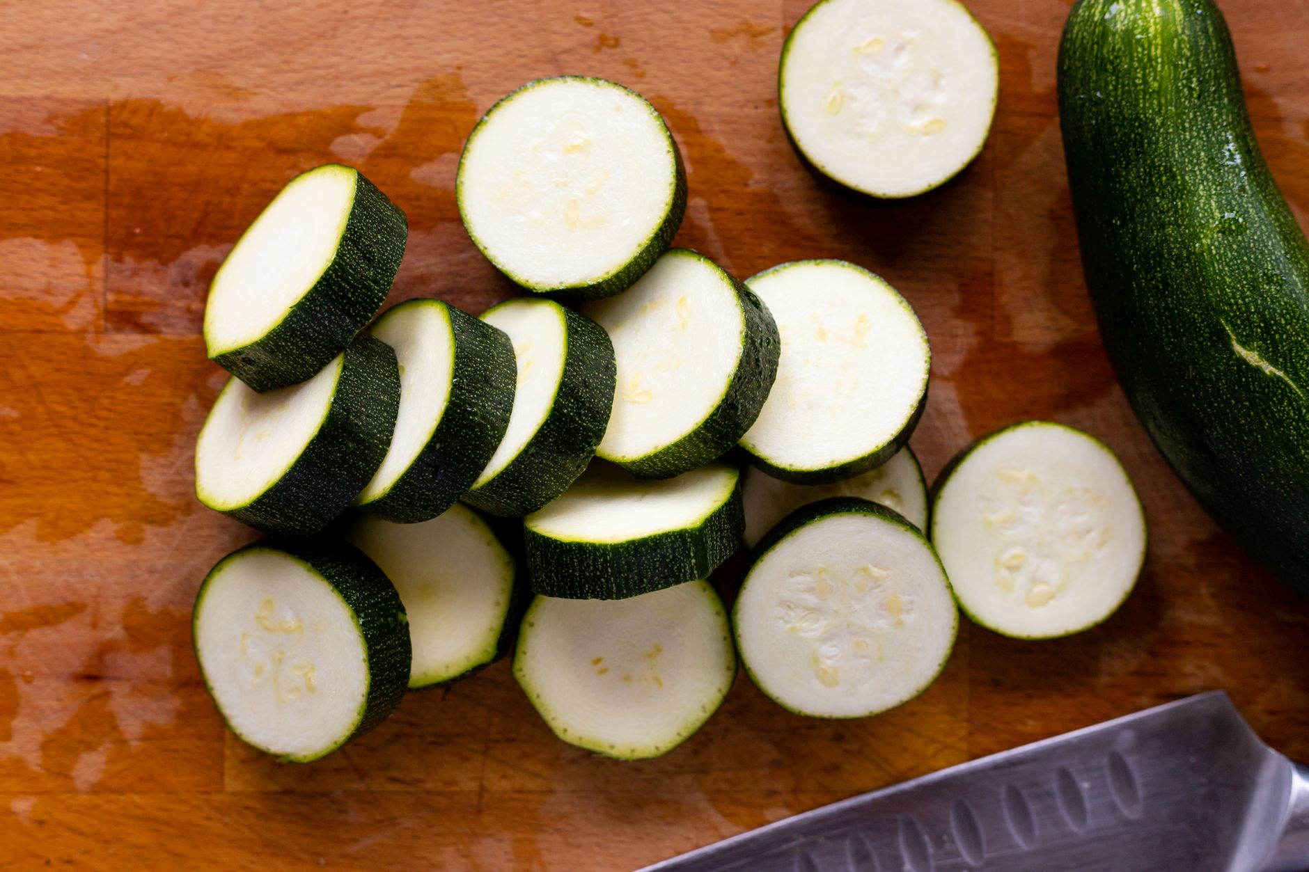 Close-up of sliced zucchini on a wooden cutting board, ready for cooking.
