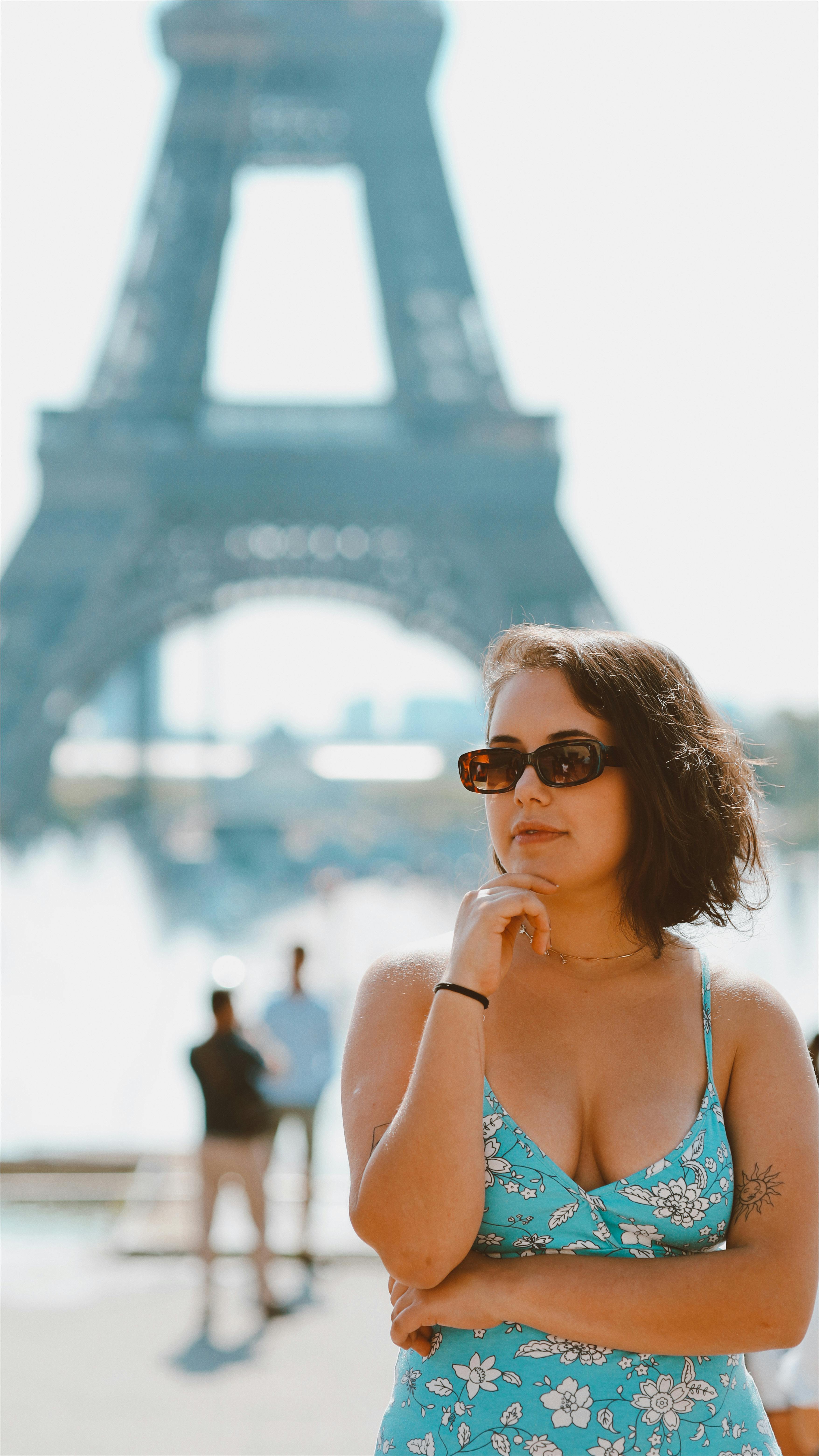 Young stylish woman in sunglasses posing near the Eiffel Tower in Paris.